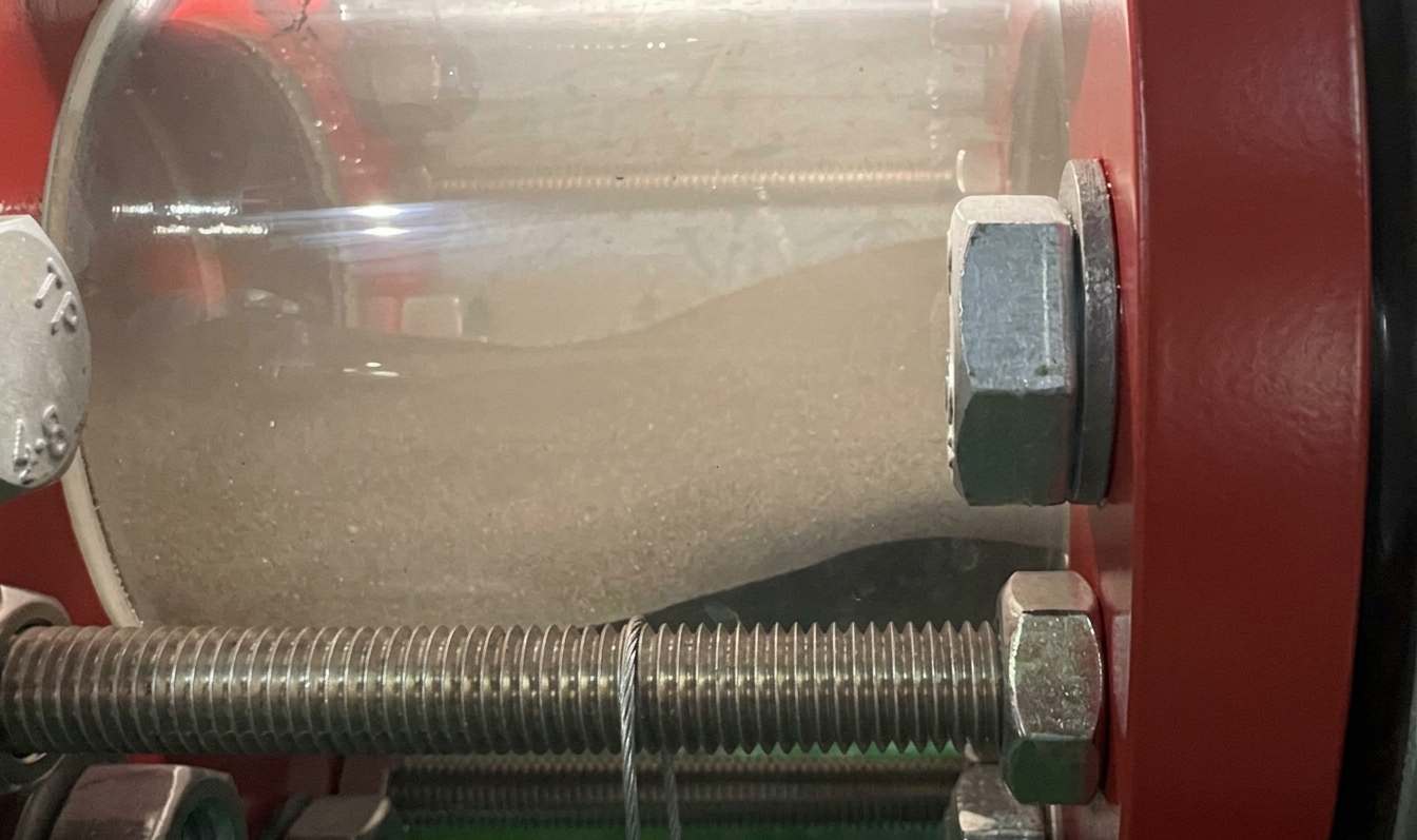 Abrasive milled slag visible through a sight glass during ultra-low-speed pneumatic conveying testing